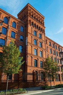 Tall brick building in sunlight, surrounded by trees and blue sky, Manufaktura, Lódz, Lodz, Lodz,