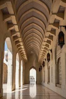 Elegant archways and intricate patterns adorn the Sultan Qaboos Mosque corridor in Muscat, Oman.