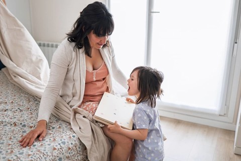 A joyful mother and her big sister daughter enjoy bonding time in a cozy home setting, sharing