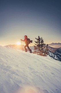 A woman's ski tour at sunrise on the Tegelberg in the Allgäu in the Ammergebirge, Bavaria, Germany