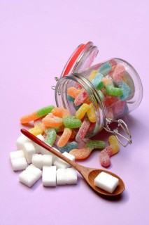 Lots of colorful jelly sweets in glass containers and sugar cubes, sugar consumption