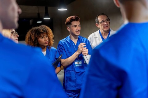 Young medical professionals and experienced doctor actively participating in a group discussion,