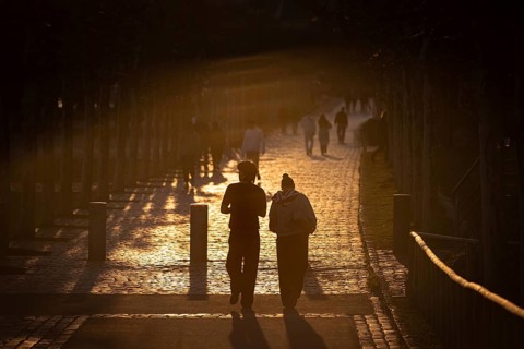 Several people walk in the evening at sunset on the banks of the Main in Frankfurt, in the area of