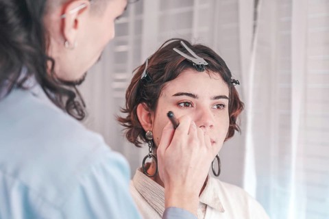 Professional makeup artist carefully applying makeup on a model's face, enhancing her natural