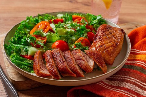 Delicious grilled duck breast served with fresh garden salad and cherry tomatoes at a rustic dining