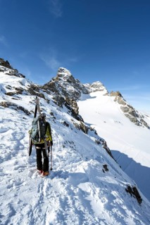 Mountaineer with skis at the fork Porta d'Es-cha, view of mountain peak Piz Kesch and glacier