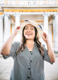 Portrait of smiling woman traveler in a tourist square. Portrait of a tourist girl with hat in a