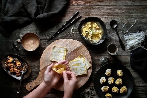 Top view of anonymous woman preparing wonton soup on a wooden table
