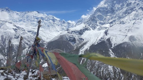 Snow-capped Himalayan mountains with waving prayer flags in the foreground, trekking at Annapurna