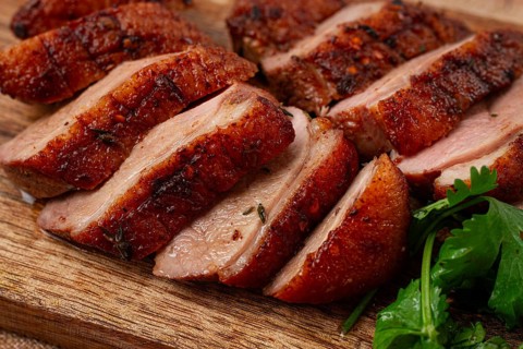 Roast duck breast, sliced, on a wooden chopping board, close-up, no people