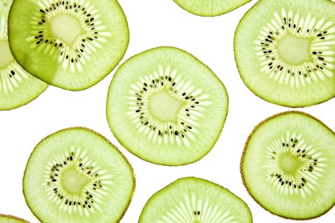 Close up of vibrant kiwi slices arranged on a light background. The image showcases the bright