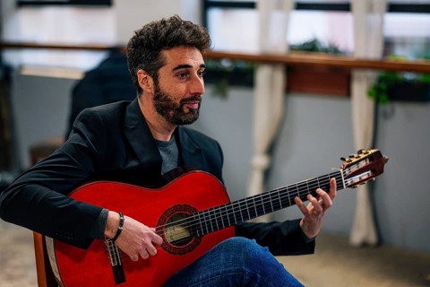 Side view of male playing guitar in music studio