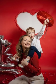 Joyful mother and young son celebrating Valentine's Day in front of a giant heart decoration,
