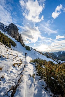 Hikers on a hiking trail with snow, sun star, ascent to Kramerspitz, in autumn, Ammergau Alps,