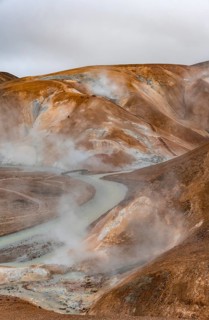 Bridge and steaming streams between colourful rhyolite mountains and snowfields, Hveradalir