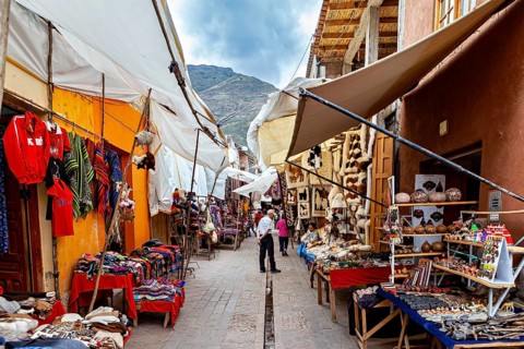 A colorful market with traditional Peruvian textiles and Andes in the background, the city of