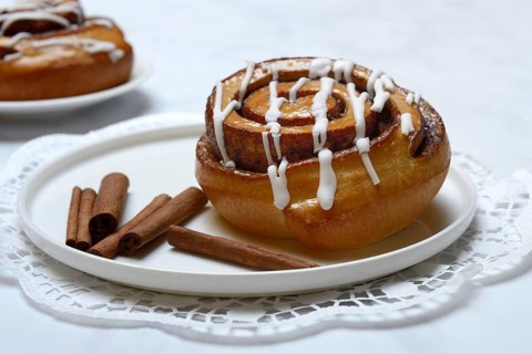 Cinnamon roll on plate and cinnamon sticks