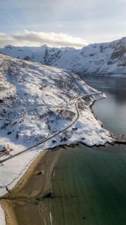 A breathtaking aerial view of a serene Nordic coastline, showcasing snow-covered landscapes, a