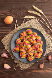 Rainbow colored dumplings with pepper, herbs, microgreen on brown wooden background and linen