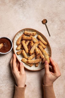 Top view of cropped unrecognizable hand on a ceramic plate filled with sugar and cinnamon coated
