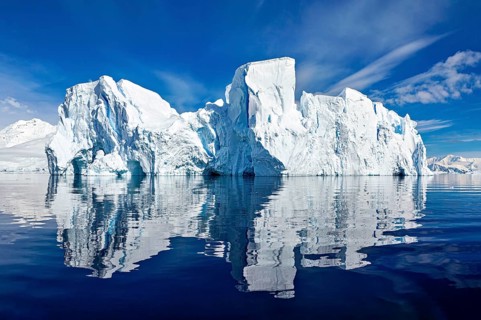 Majestic icebergs are reflected in the calm waters under a clear blue sky, icebergs in the Southern
