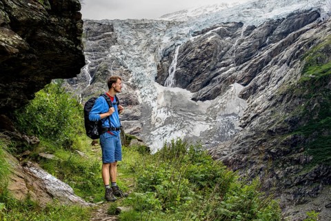 Mountaineers on a hiking trail in front of glaciers, cloudy mountain landscape with
