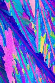 Vibrant microscopic image displaying the crystalline structure of Adipic acid, featuring striking