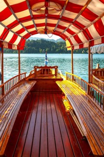 Wooden tourist boat with red and white canopy sailing on lake bled in slovenia, offering scenic