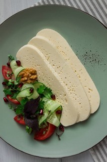 Sliced Imeruli cheese, Georgian cheese, with vegetables, top view, no people