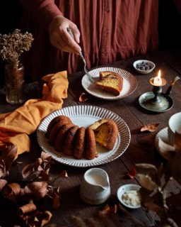 A cozy scene featuring a homemade pumpkin cake on a wooden table. Warm lighting highlights the