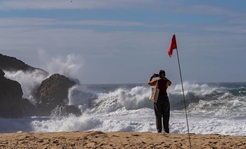 Tourists watch the waves of the Atlantic on the rocky plateau of Sito, also known as Forte São