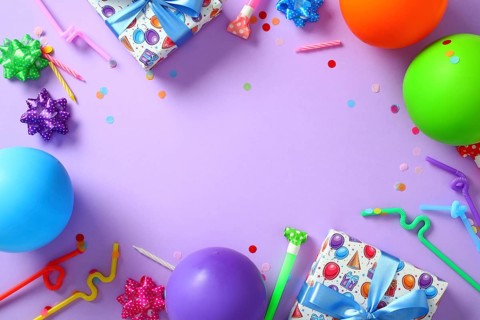 Colorful birthday party flat lay frame on purple background with copy space