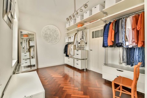 A sleek and modern walk in closet featuring an open storage system with neatly organized clothes,