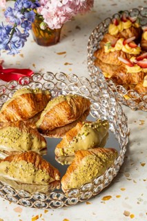 Elegant arrangement of croissants topped with pistachio cream, served on a crystal tray,