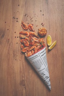 Fried shrimp, in a paper bag, shrimp for beer, in a newspaper, on a gray table, no people