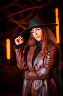 Girl in a hat in a portrait at night on a parcel. Caucasian brunette model looking at camera,