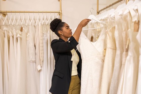 A woman explores various bridal gowns in an elegant boutique, selecting the ideal wedding dress.
