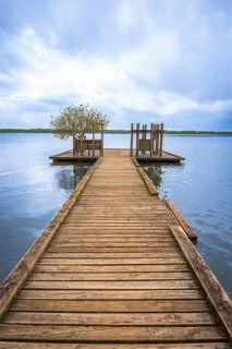 Wooden pier stretching into the calm blue water of lake azur, leading to an observation platform