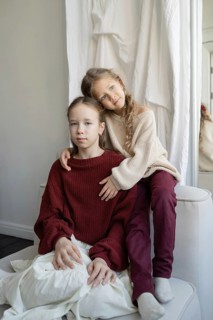 Two young sisters share a tender moment at home, dressed in cozy sweaters The loving embrace