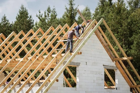 Two men work on the roof of house construction