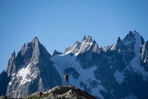 Young man in front of impressive mountain landscape in morning light, pointed rocky icy mountain