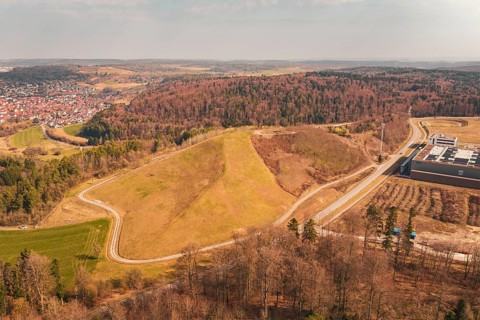 Extensive landscape with hills and forests, city visible from a bird's eye view in the distance,