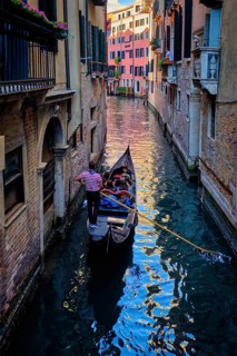 VENICE, ITALY, JUNE 27, 2018: Narrow canal between colorful old houses with gondola boat with