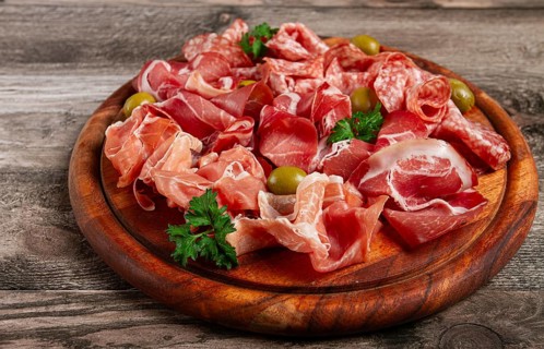 Assortment, sliced meat appetizer, prosciutto, salami and ham, with olives, on a wooden board,
