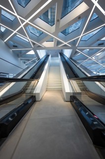 Modern escalator in a futuristic building with geometric ceiling and glass roof, Porsche Museum,