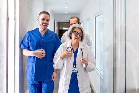 Healthcare professionals, including a female doctor and a male nurse or surgeon, walking and