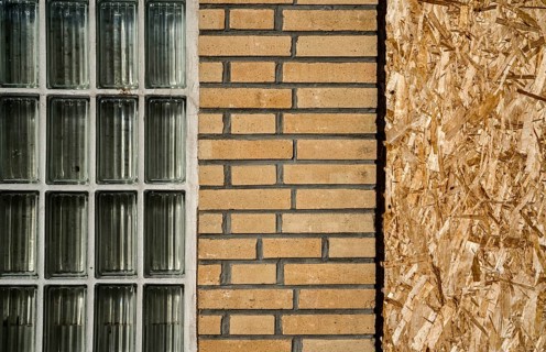 Old building with brick walls and a window covered with OSB panels