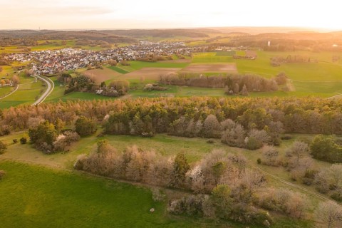 Panorama of fields, forests and a village in warm evening light, e-bike tour, old sports ground in