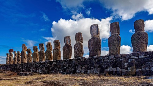 Moai statues on wall standing out against a sky with white clouds, The Moai statues on Easter