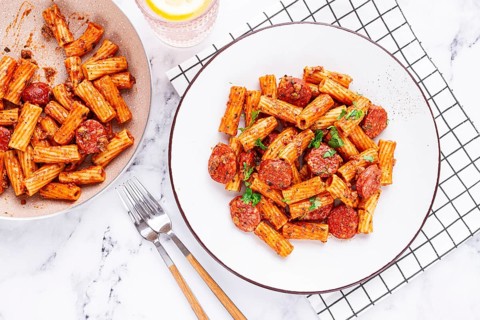 Rigatoni pasta with spicy sausage, and rich tomato sauce served, on a white plate, homemade